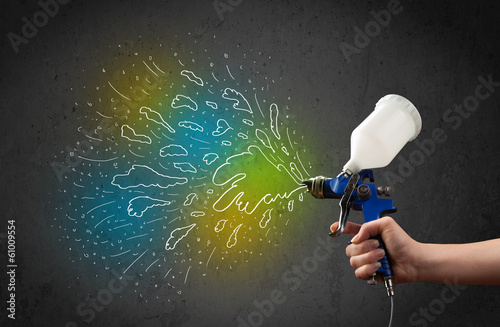 Worker with airbrush gun paints colorful lines and splashes