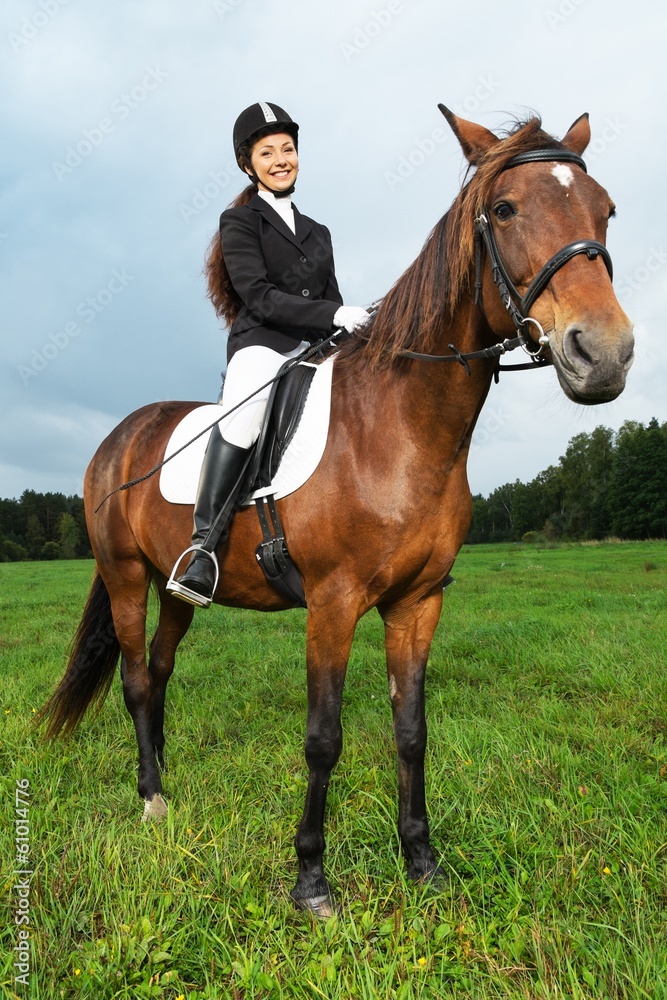 Cheerful young woman ridding horse in a field