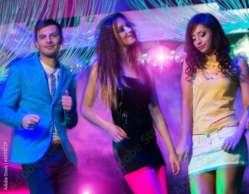 Group of happy young people dancing at night club