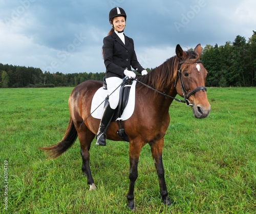 Cheerful young woman ridding horse in a field