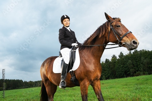 Cheerful young woman ridding horse in a field