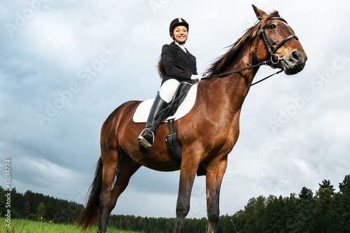 Cheerful young woman ridding horse in a field
