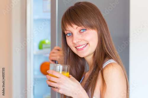 Young caucasian brunette girl with a glass of juice in the kitch