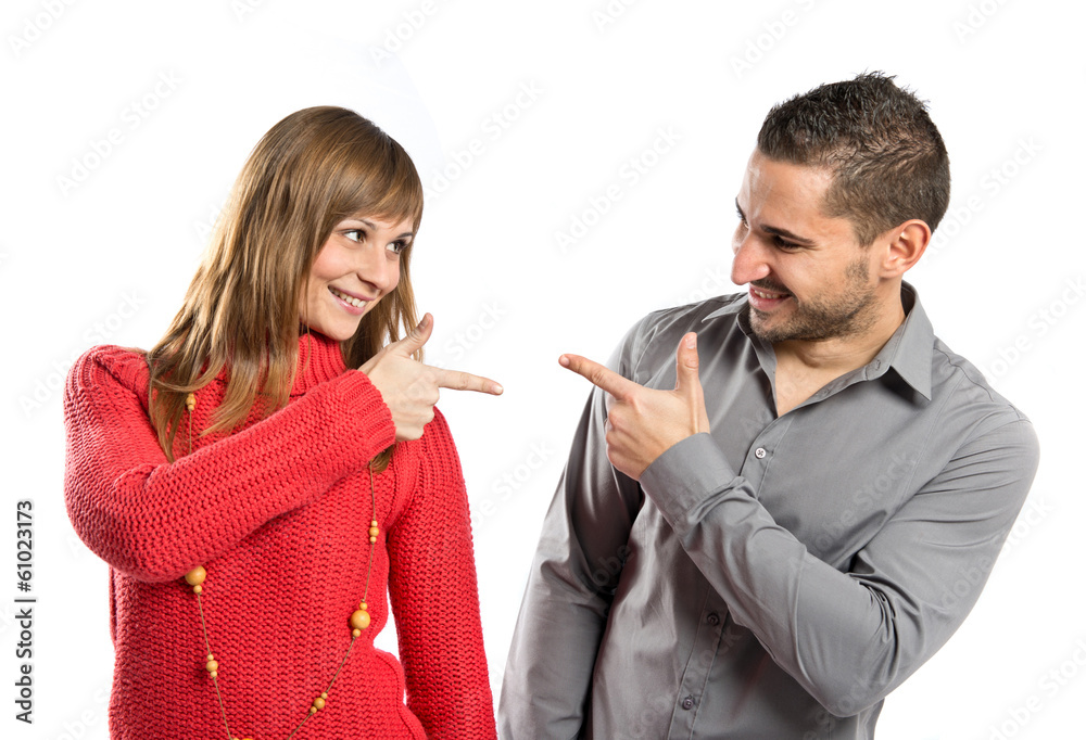 Couple pointing each other over white background Couple pointing each other over white background