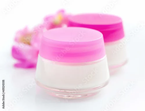 Obraz Cosmetic creams  and pink flowers isolated on white background