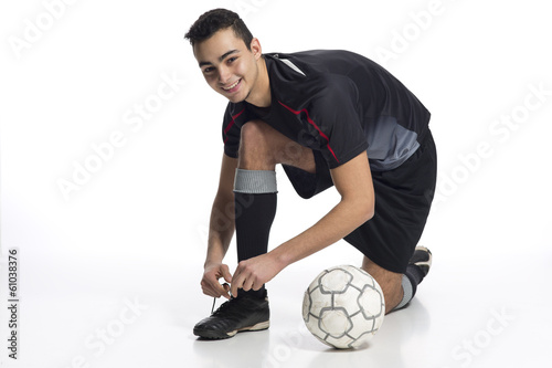 junger Fussballer kniet sich zum Zubinden der Schuhe