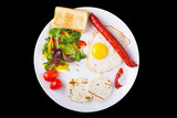 Fried egg and sausage on the plate with green salad and cheese
