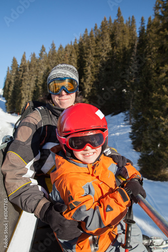 The father with son on chair lift in mountains
