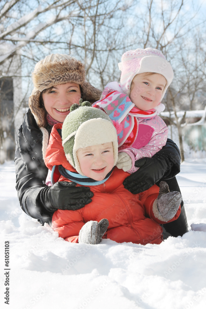 Mother with two children lying in snow