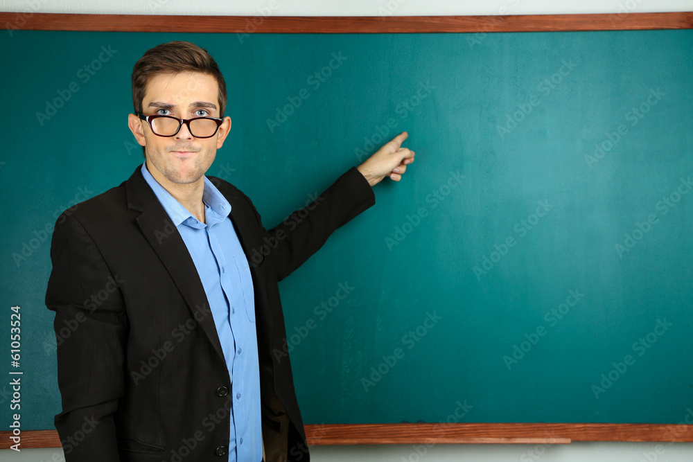 Young teacher near chalkboard in school classroom Young teacher near chalkboard in school classroom