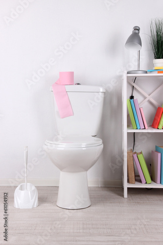 White toilet bowl and stand with books, on color wall © Africa Studio