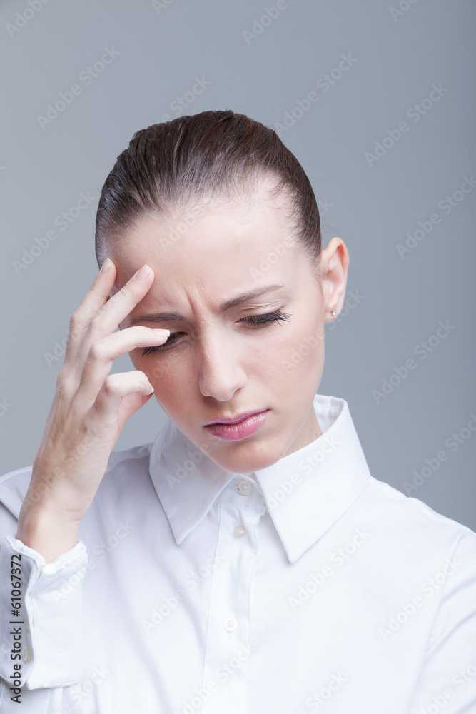 Woman having a headache holding her forehead in pain Woman having a headache holding her forehead in pain