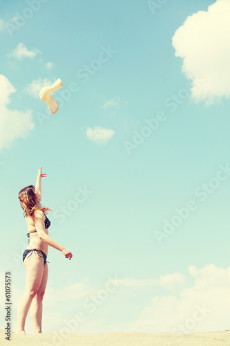 Young woman in bikini is throwing high her summer hat. © Piotr Marcinski