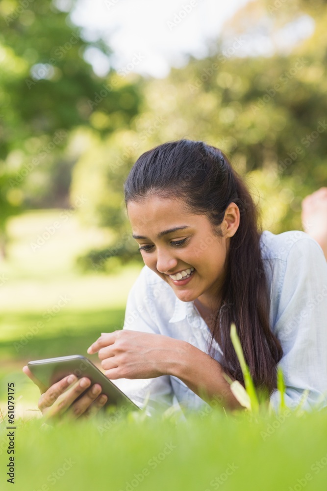 Smiling woman text messaging while relaxing in park Smiling woman text messaging while relaxing in park