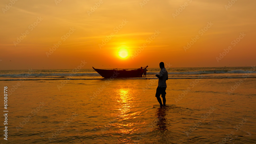 Fisherman and boat against the setting sun