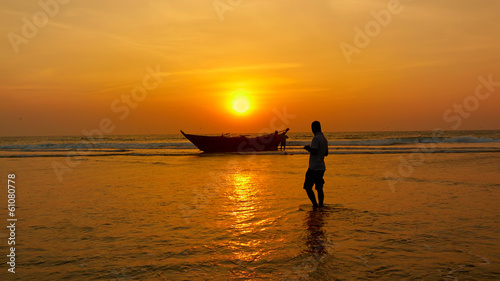 Fisherman and boat against the setting sun