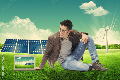 Giovane uomo con laptop seduto in un parco energetico