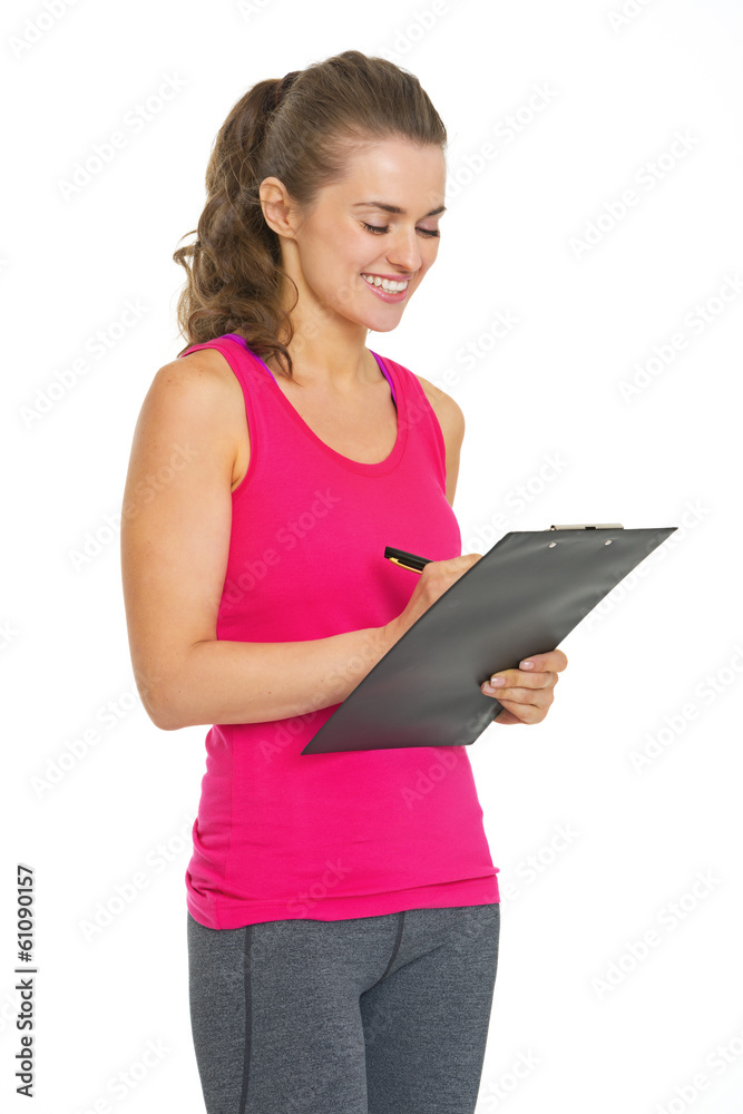 Smiling fitness young woman writing in clipboard Smiling fitness young woman writing in clipboard