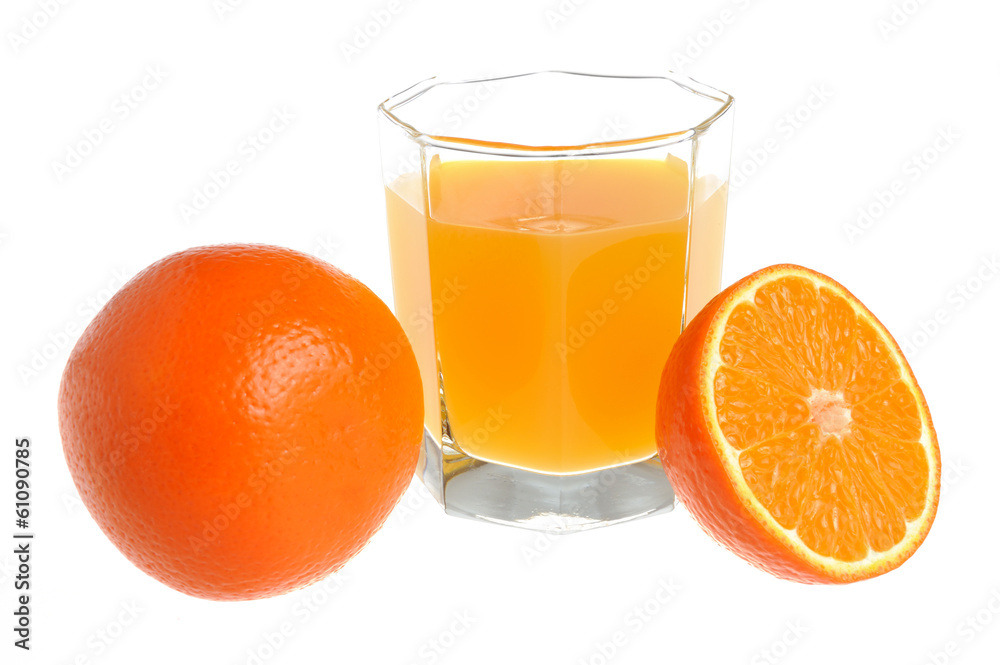 A half and a whole orange with a glass filled with citrus juice A half and a whole orange with a glass filled with citrus juice