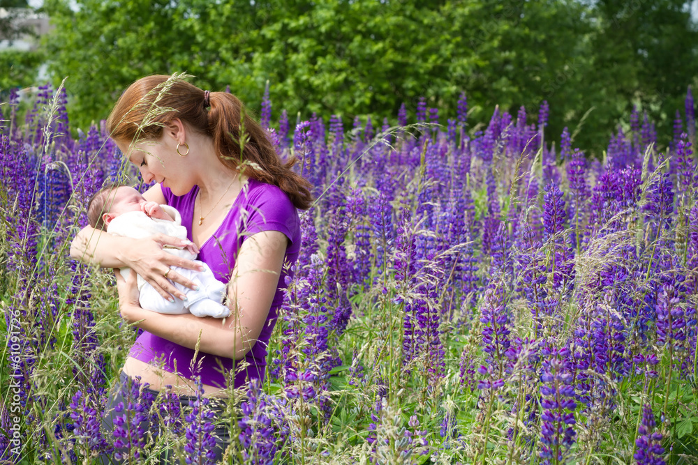 Young mother with her newborn baby in purple lupines field Young mother with her newborn baby in purple lupines field