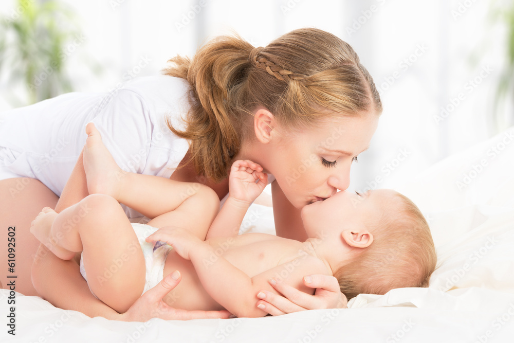 Naklejka premium happy family mother and baby having fun playing, laughing on bed