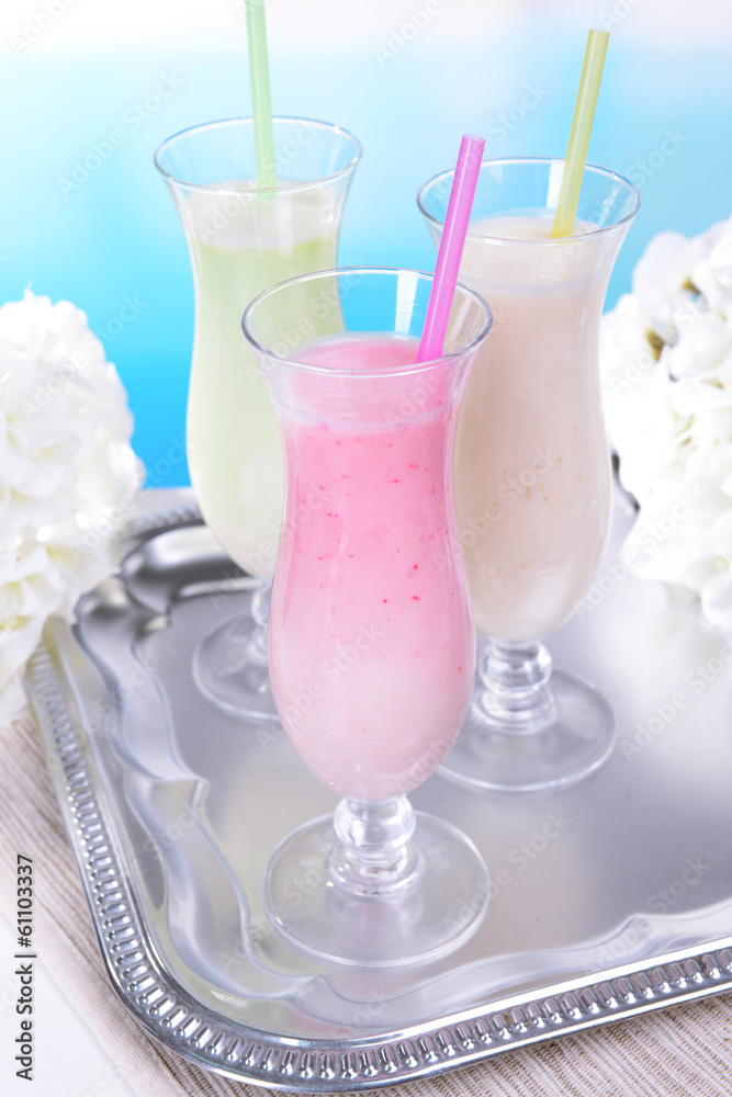 Milk shakes on table on light blue background Milk shakes on table on light blue background