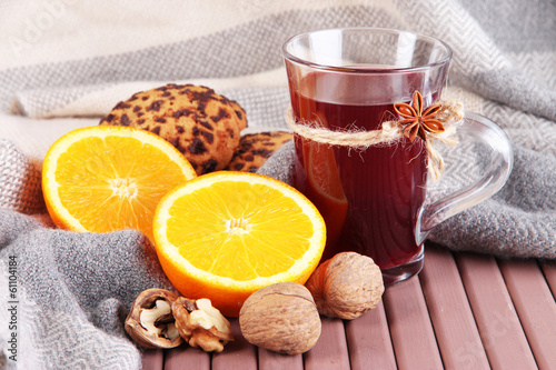 Mulled wine with oranges and nuts on table on fabric background