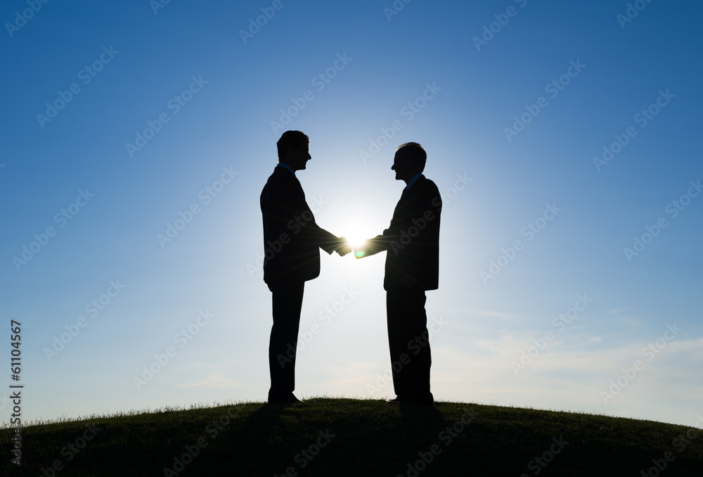 Silhouette of Two Businessmen Shaking Hands Silhouette of Two Businessmen Shaking Hands