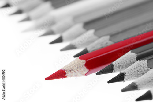 One red pencil standing out from grey pencils. Leadership
