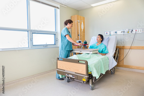 Nurse Bringing Breakfast For Male Patient In Hospital