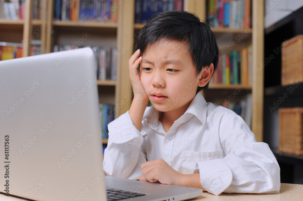 Asian boy thinking hard in front of laptop computer Asian boy thinking hard in front of laptop computer