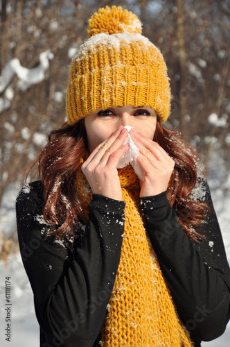 Woman sneezing into tissue, winter outdoor portrait