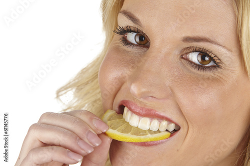 Junge Frau beisst in eine Zitronenscheibe