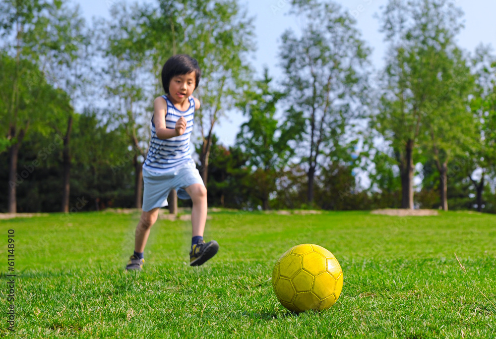 Young Asian boy kicking a yellow ball Young Asian boy kicking a yellow ball