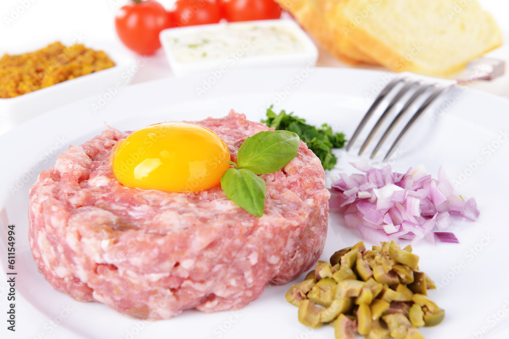 Delicious steak tartare with yolk on plate on table close-up