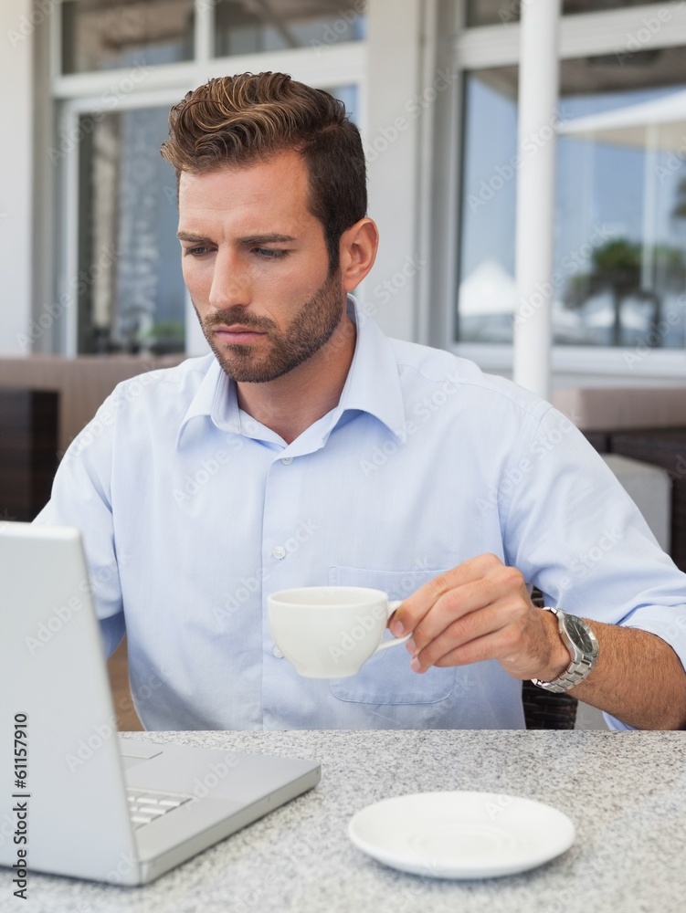 Concentrating businessman working with laptop at table Concentrating businessman working with laptop at table