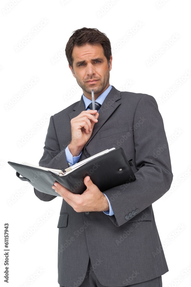Handsome thinking businessman holding his diary Handsome thinking businessman holding his diary