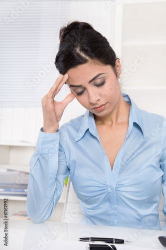 Junge Frau mit Migräne und deprimiert sitzend im Büro