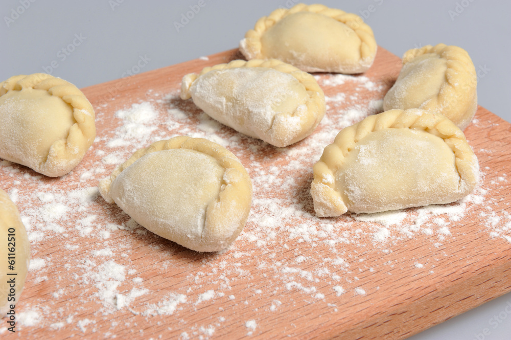 Uncooked floured pelmeni with a pattern on the cutting board on Uncooked floured pelmeni with a pattern on the cutting board on