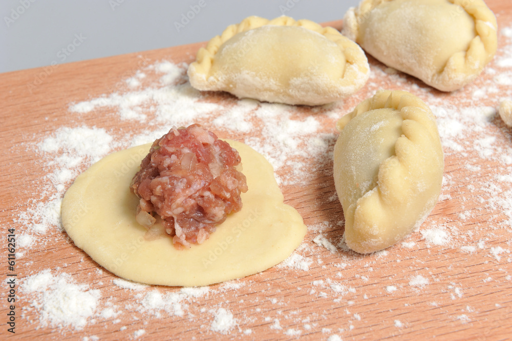 Uncooked floured pelmeni with a pattern on the cutting board on Uncooked floured pelmeni with a pattern on the cutting board on