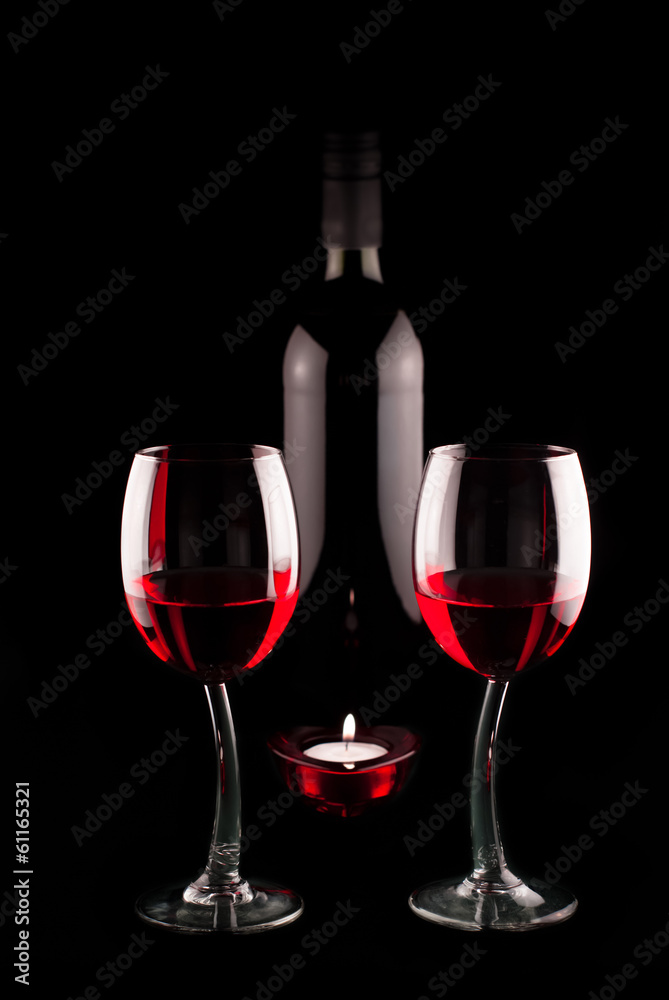 two glasses and a bottle of red vine with heart shaped candle