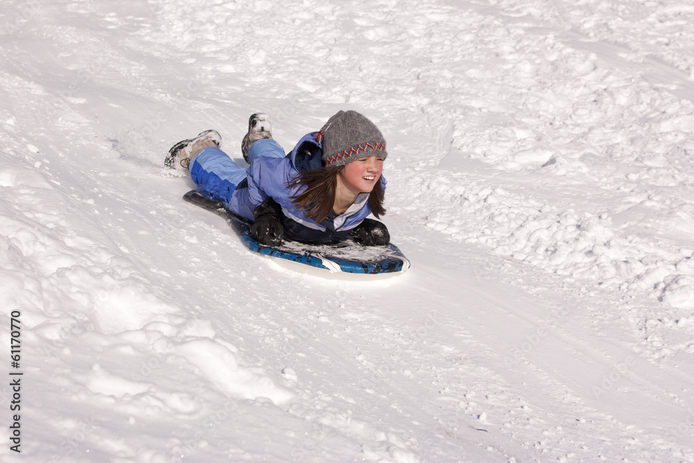 Girl sleds down hill.