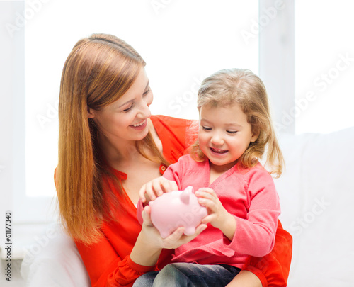 happy mother and daughter with small piggy bank