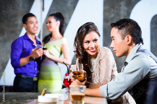 Asian couples flirting and drinking at nightclub bar