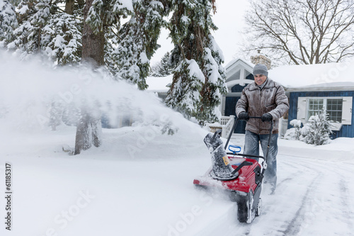Man clearing driveway with snowblower photo