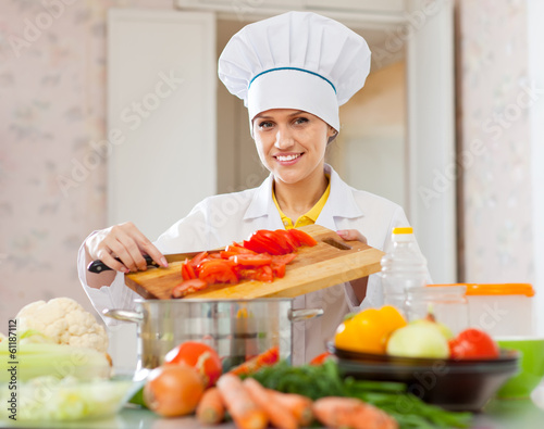 Happy cook in toque works with vegetables