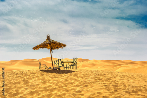 Sun umbrella and chairs in desert