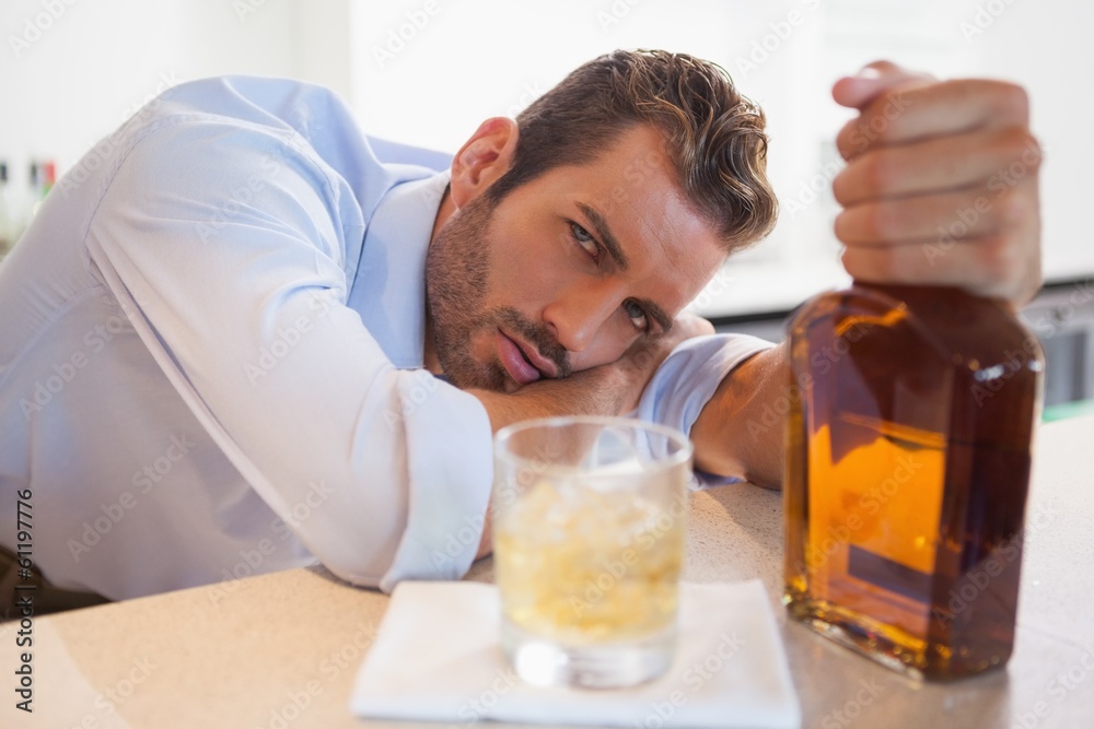 Drunk businessman clutching whiskey bottle looking at camera Drunk businessman clutching whiskey bottle looking at camera