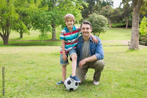 Portrait of father and son with ball at park