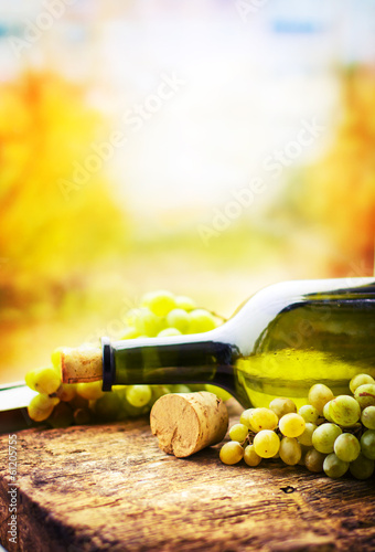 Fototapeta Naklejka Na Ścianę i Meble -  Bottle of white wine, grape and corks on wooden table